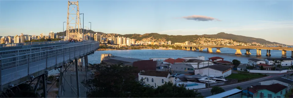 Ponte Hercílio Luz ao entardecer, com a orla e os morros de Florianópolis ao fundo