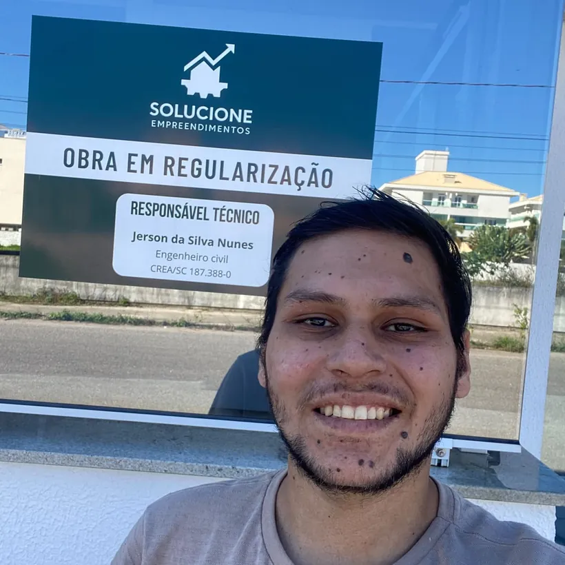 Jerson Nunes, engenheiro civil responsável técnico da Solucione, diante da placa de uma obra em processo de regularização.